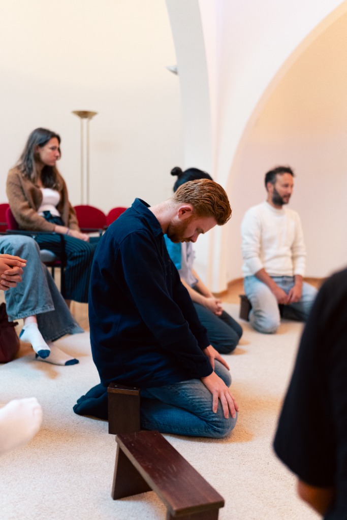 Jongvolwassenen in stilte en gebed in een kapel bij Magis